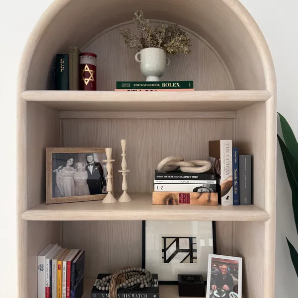 A styled arched bookshelf with decor objects